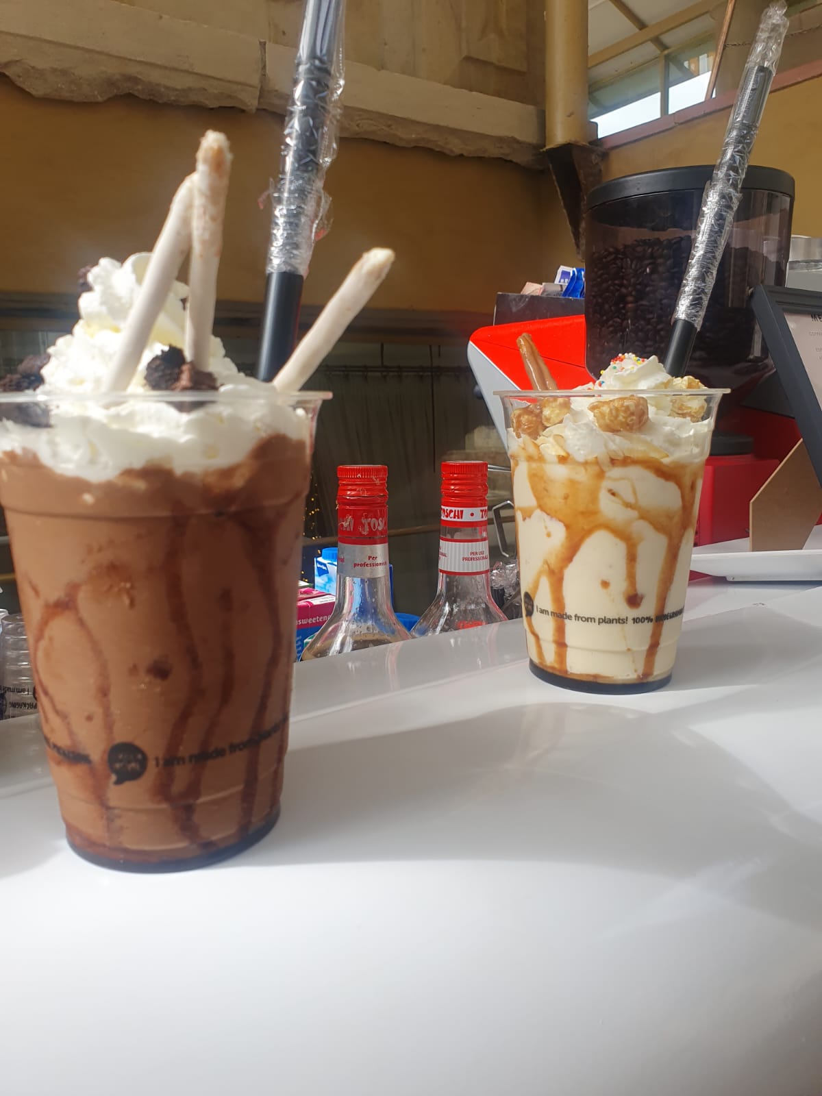 Two bubble tea drinks with toppings on a white counter.