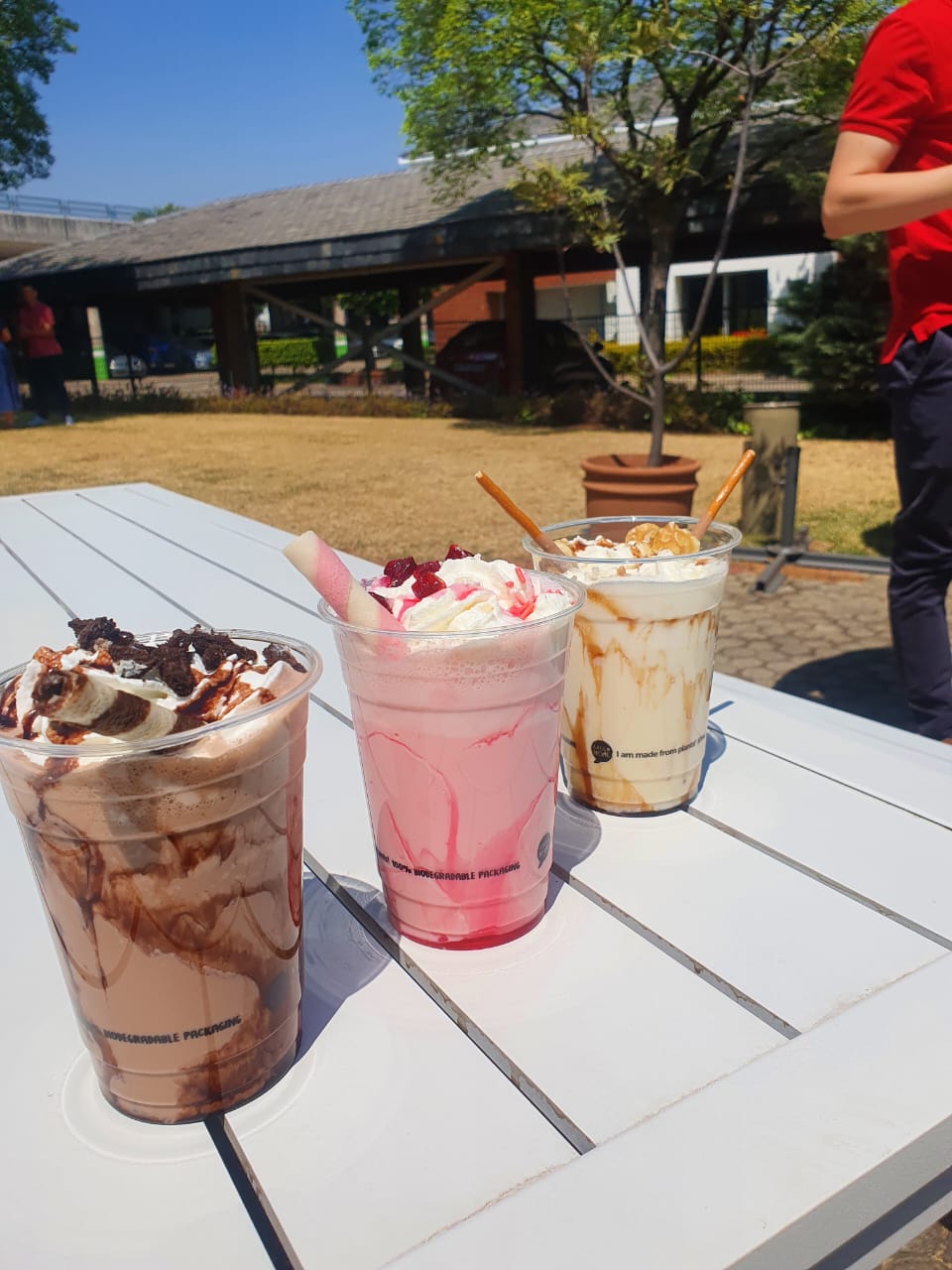 Three different dessert beverages in clear cups on a white table.