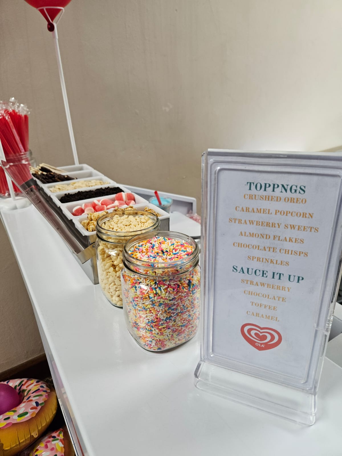 Dessert toppings station with jars of sweets and a menu sign