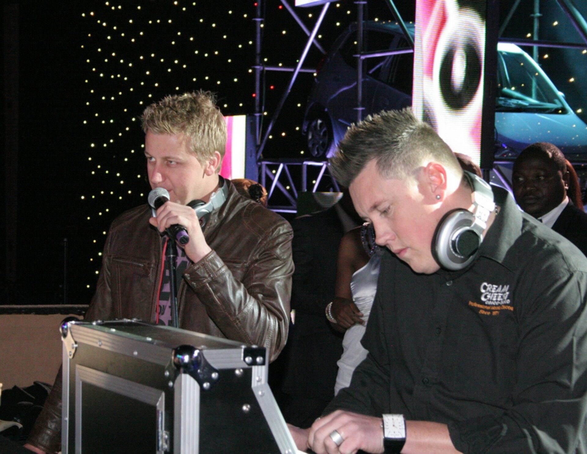 Two DJs performing live on stage with audio equipment
