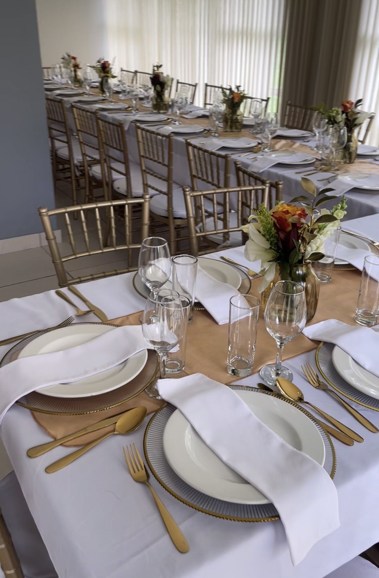 Elegant dining table with gold cutlery and floral centerpieces.