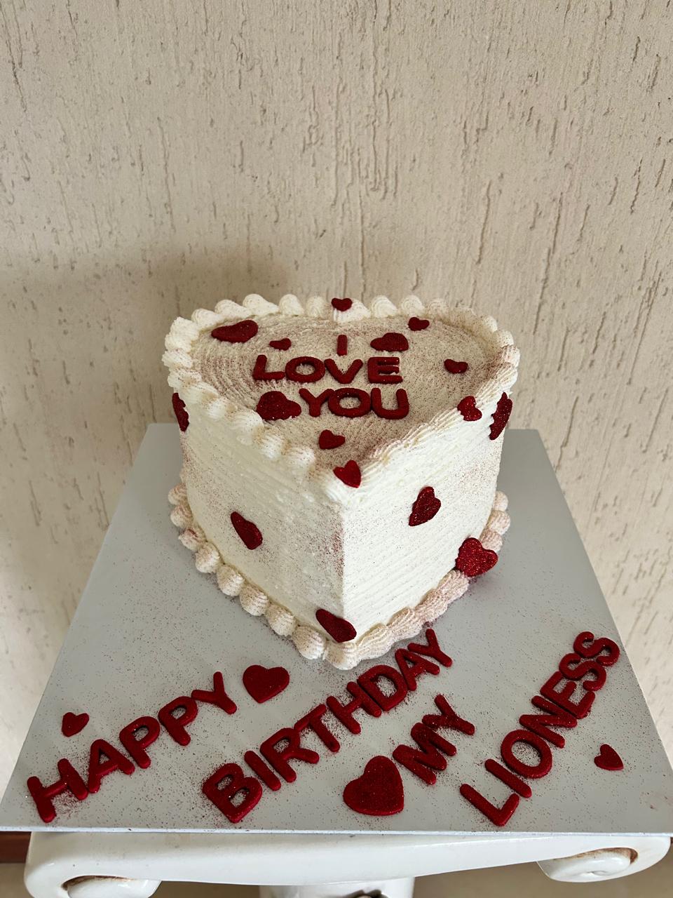 Heart-shaped birthday cake with red text and decorations.