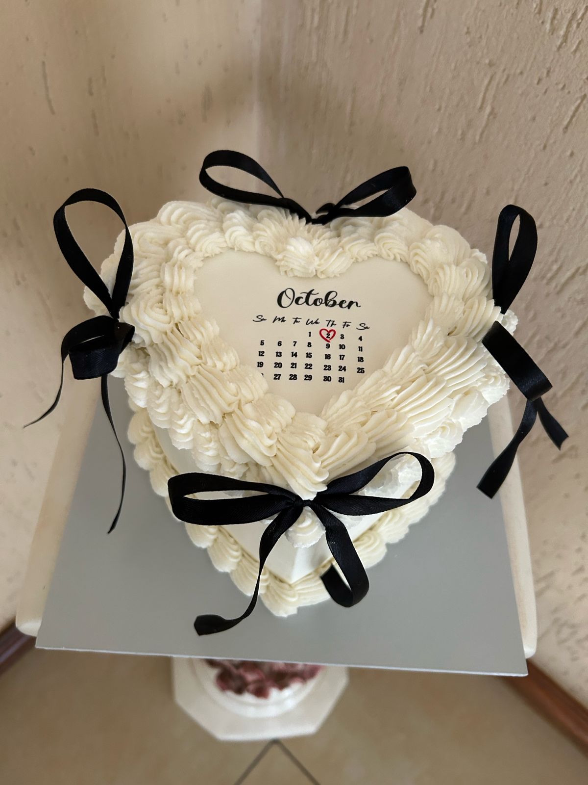 Heart-shaped cake with white frosting and black ribbons