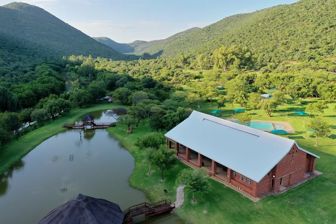 A chapel venue surrounded by green hills and a pond.