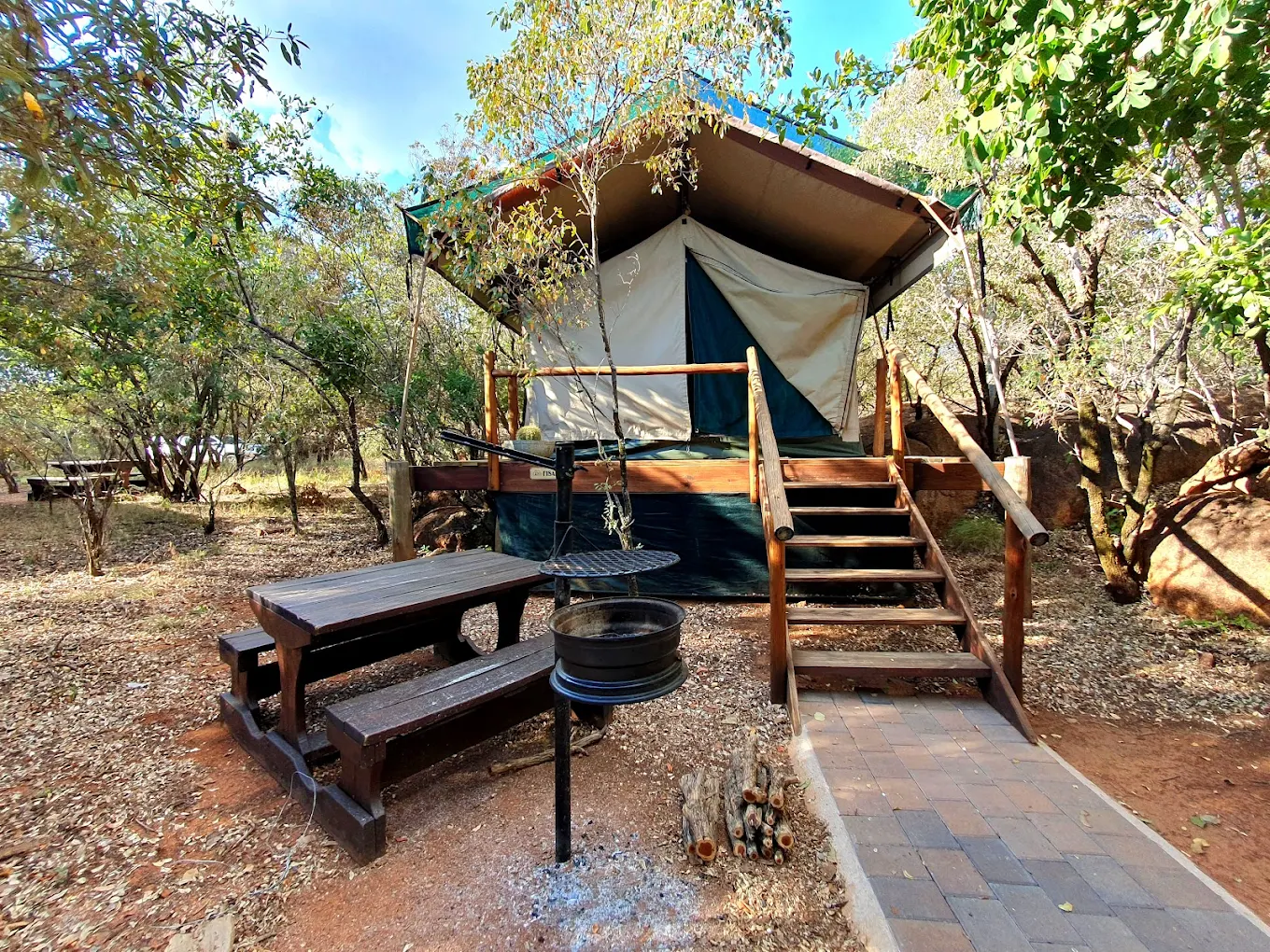 A safari tent with wooden steps in a forest