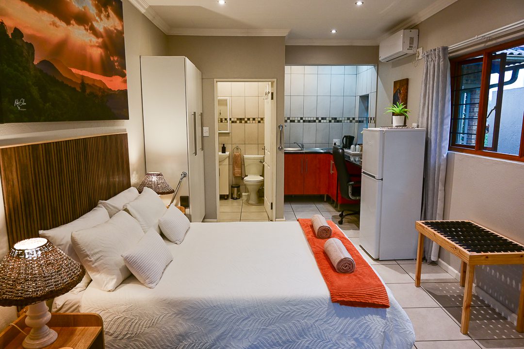 A cozy bedroom with a kitchenette and soft lighting.