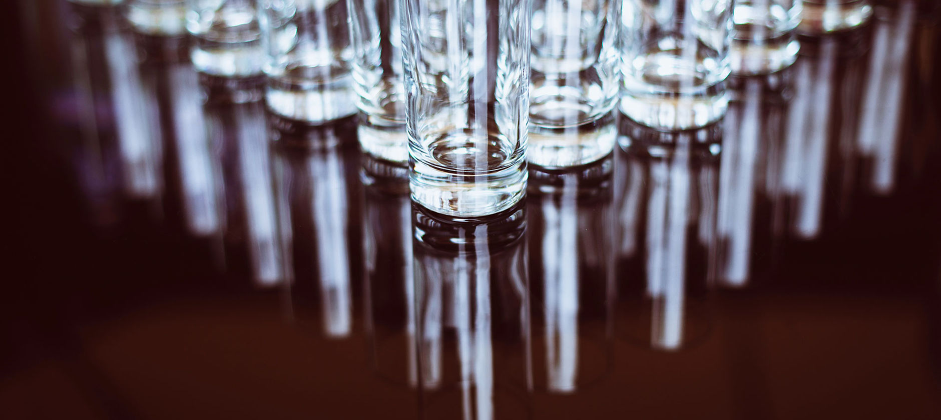 Row of clear crystal drinking glasses on a reflective surface