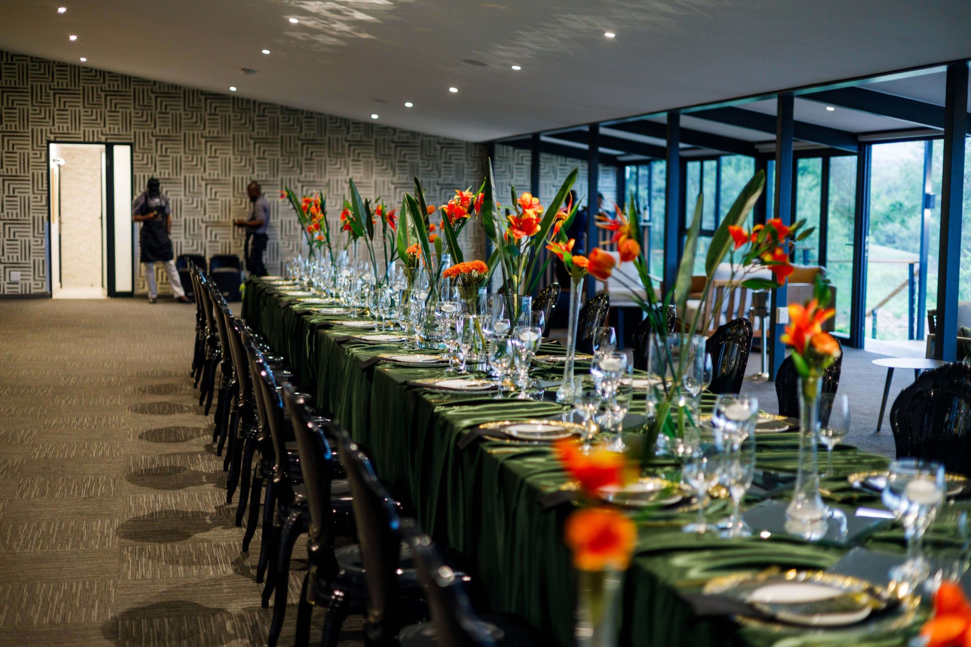 Long dining table with green tablecloth and floral centerpieces