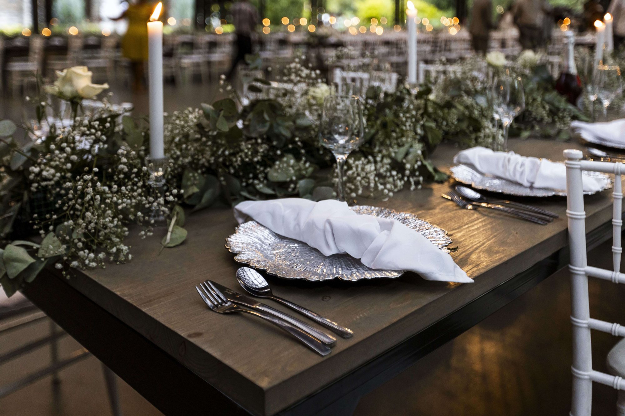 Table set with plate, napkin, cutlery, and floral decor.