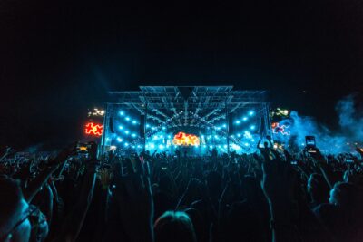 Illuminated stage with audience hands raised at a nighttime event