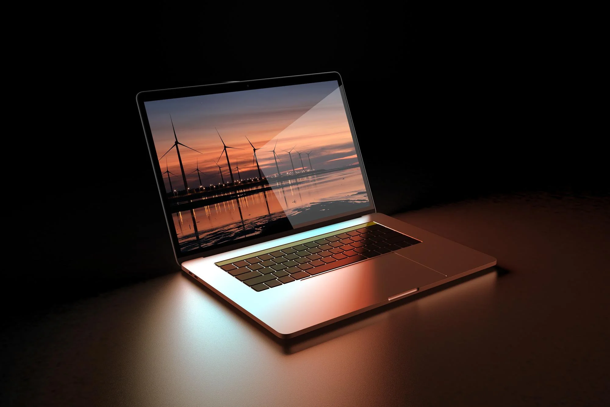 Laptop displaying sunset and wind turbines on screen.