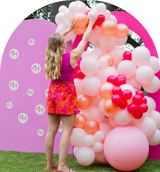 Person assembling a colorful balloon installation outdoors.