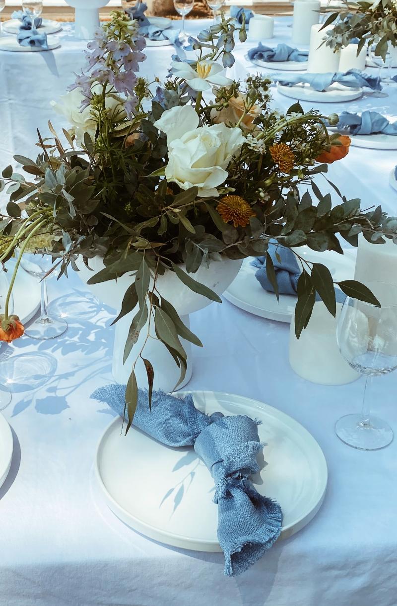 Floral centerpiece on a dining table with blue napkin