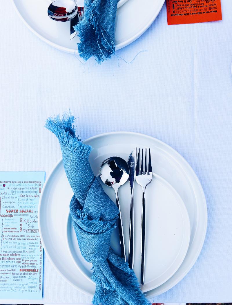 White plates with cutlery and blue napkins on a table