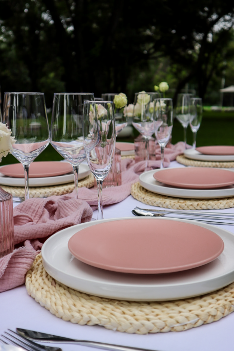 Table set with pink plates and glassware in a garden setting