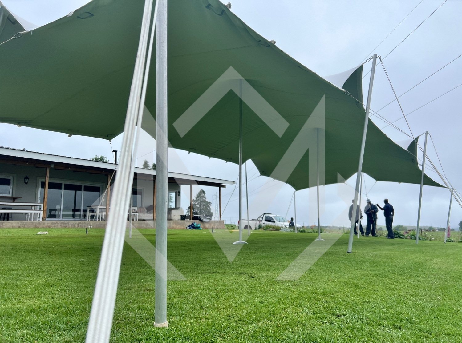 Installed stretch tent on grass with setup team in the background