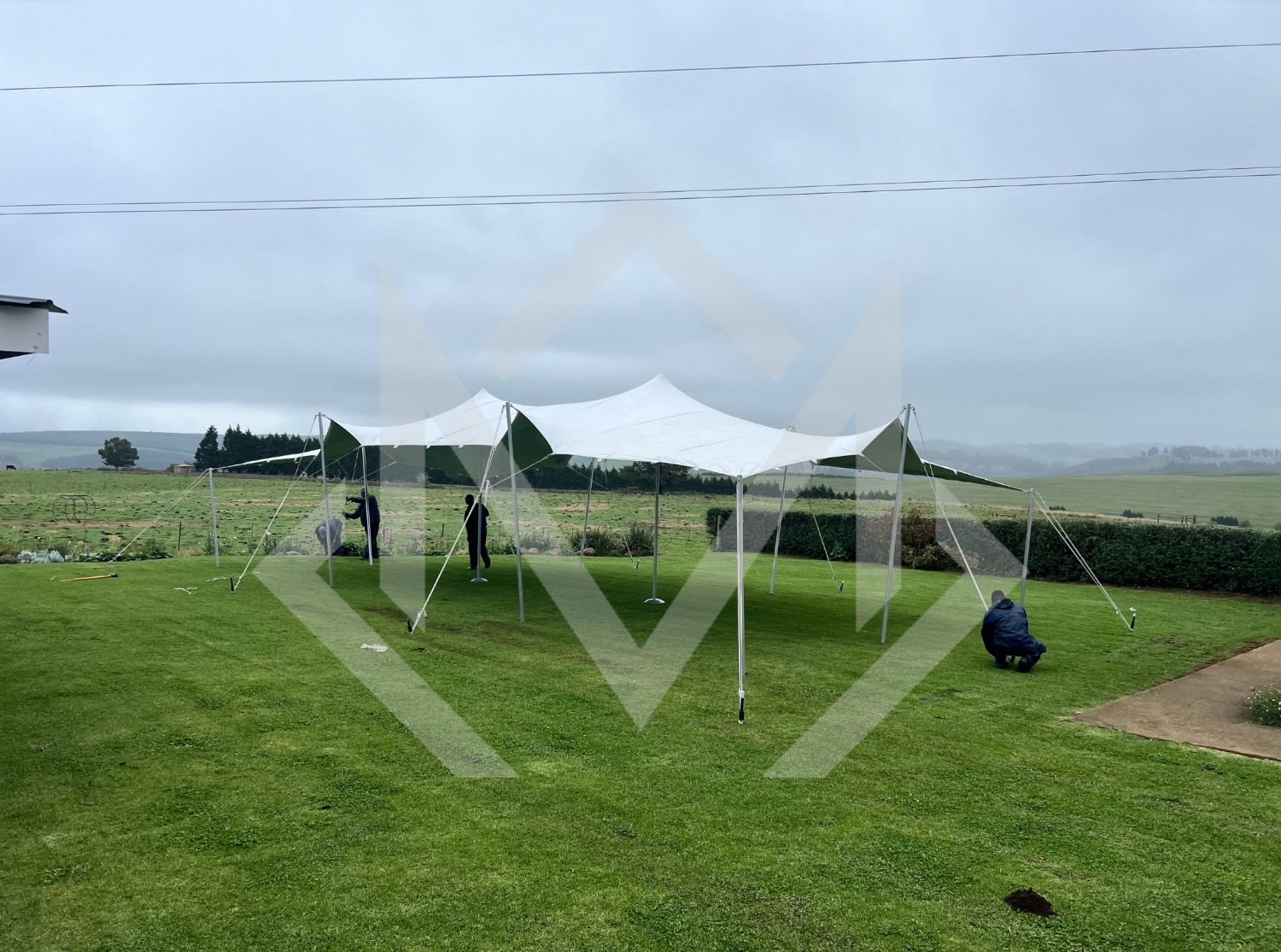 Workers setting up a stretch tent on grass