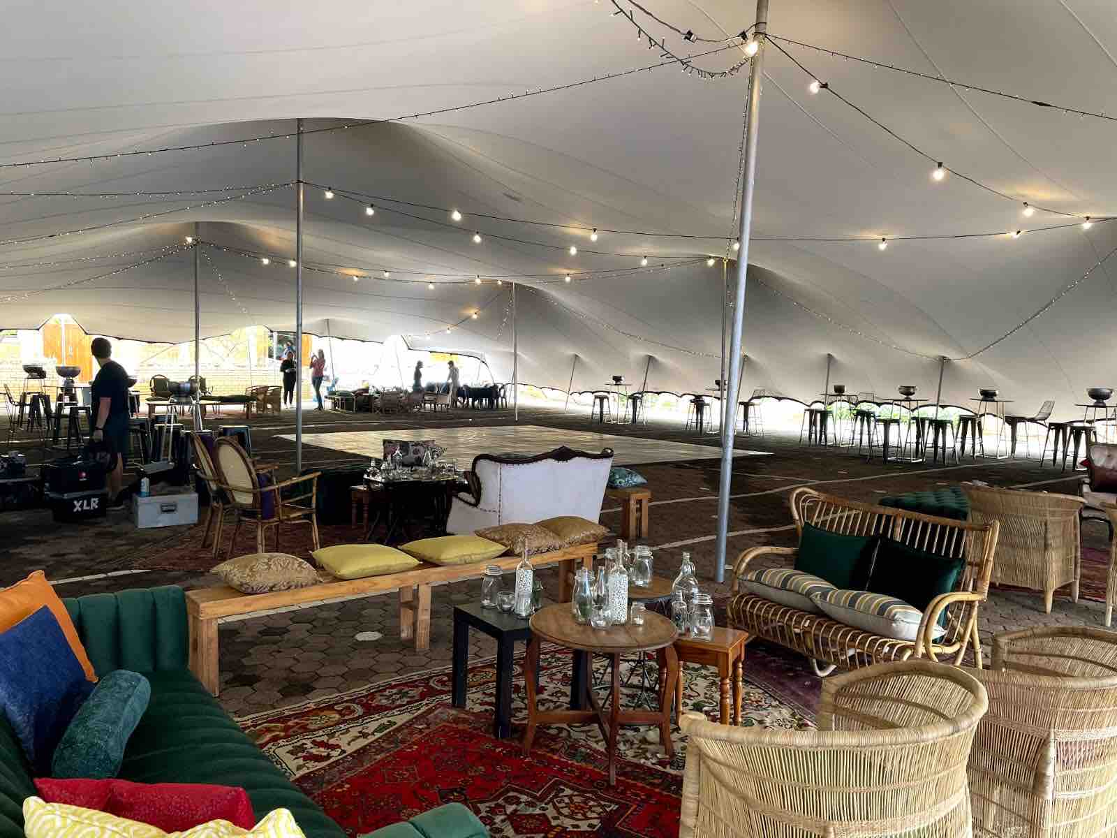 Interior of a spacious stretch tent with seating and lighting.