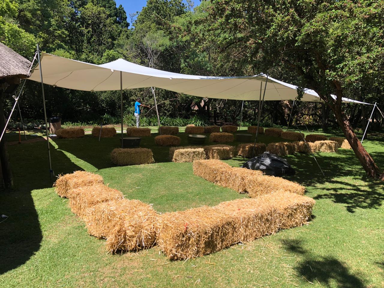 Stretch tent setup with straw bales on green grass.