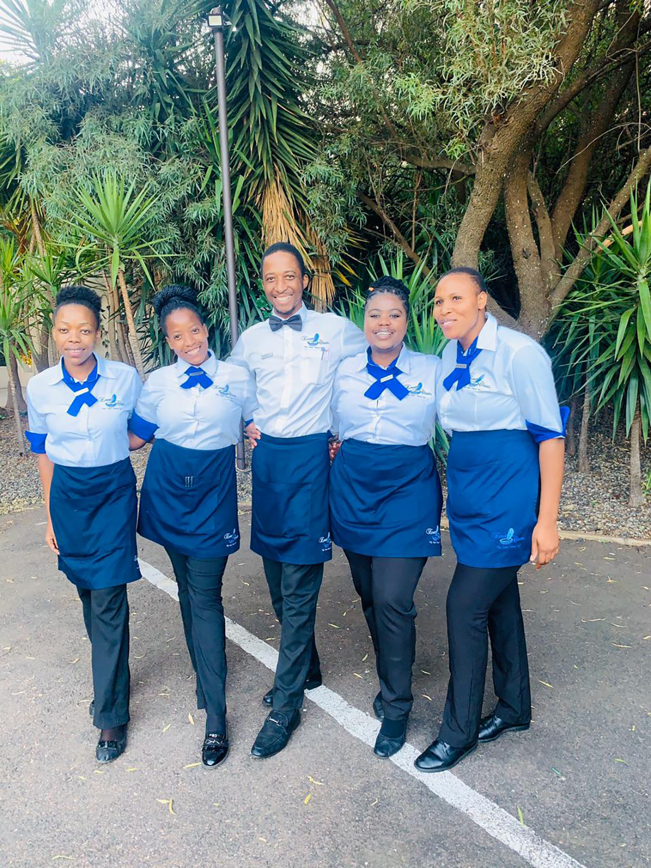 Group of hospitality staff in uniforms posing outdoors