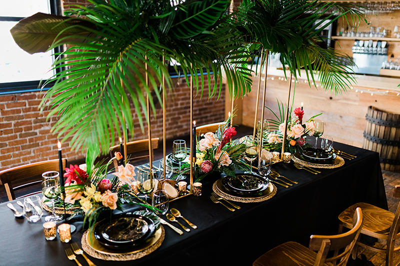 Tropical-themed dining table with greenery and floral arrangements.