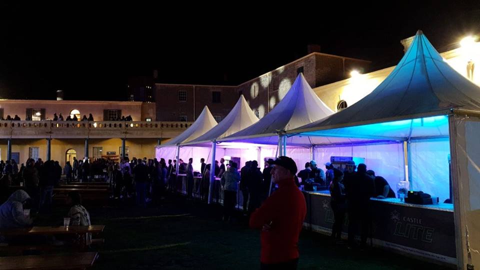 Outdoor event setup with tents and guests in the evening