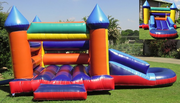 A vibrant jumping castle with attached slide in a grassy area.