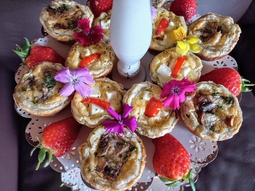 Plate of gourmet mini quiches with strawberries and flowers