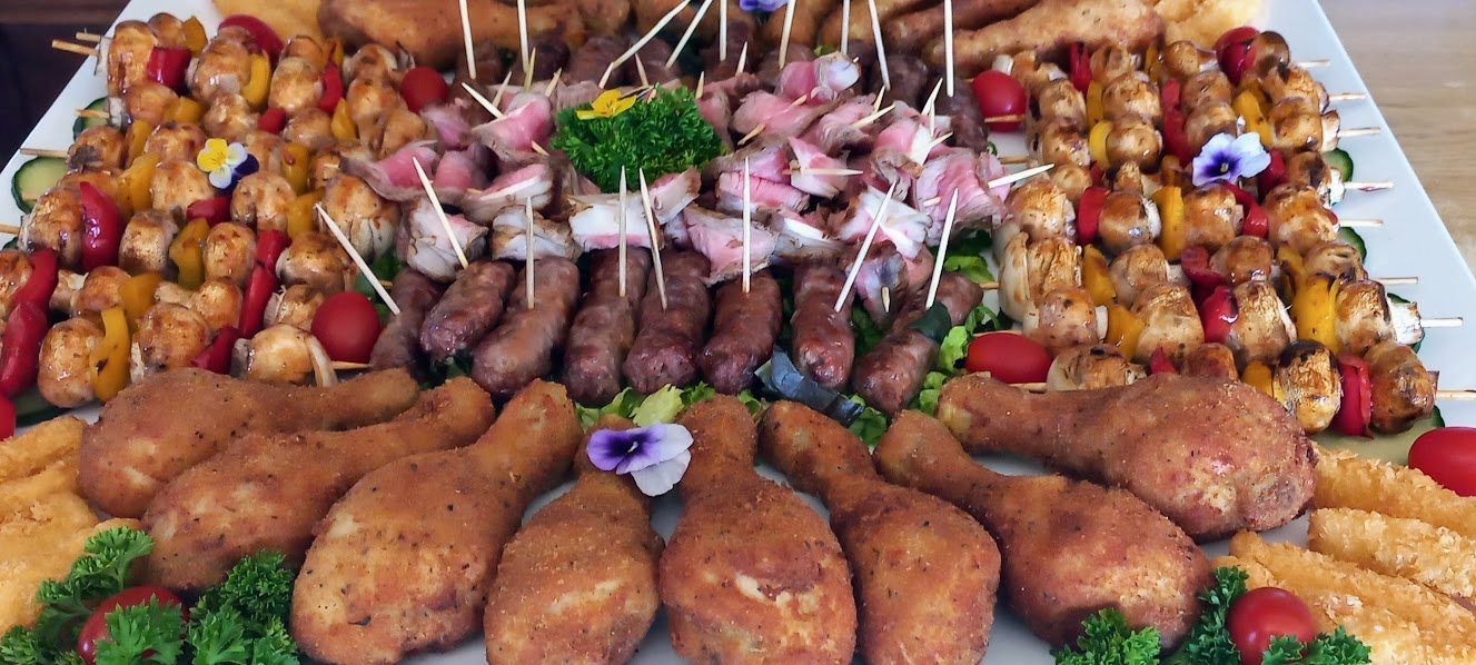 A beautifully arranged platter of finger foods including kebabs, chicken, and sausages.