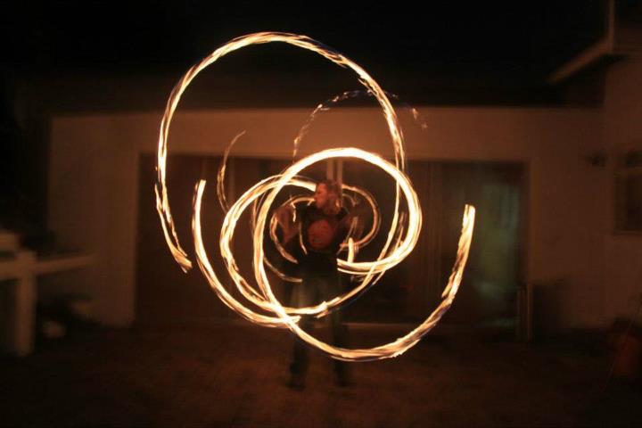 Fire poi performer creating flaming patterns at night