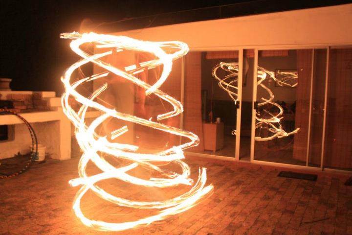 Fire poi dancer performing with glowing flames at night