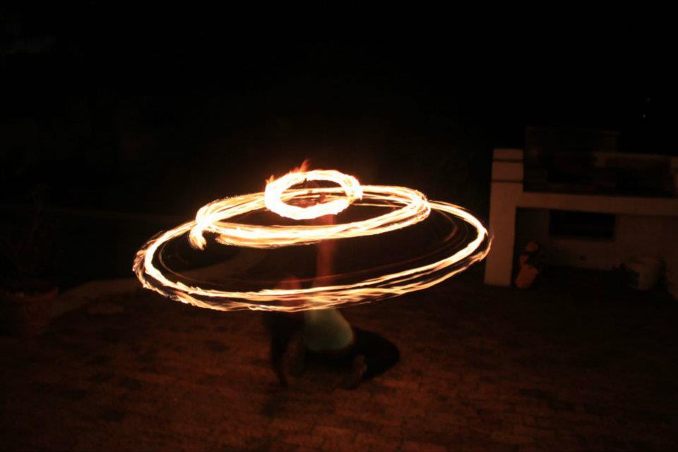 Fire poi dancer creating circular fire trails at night