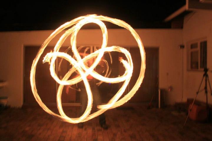 Performer showcasing fire poi with swirling flames.