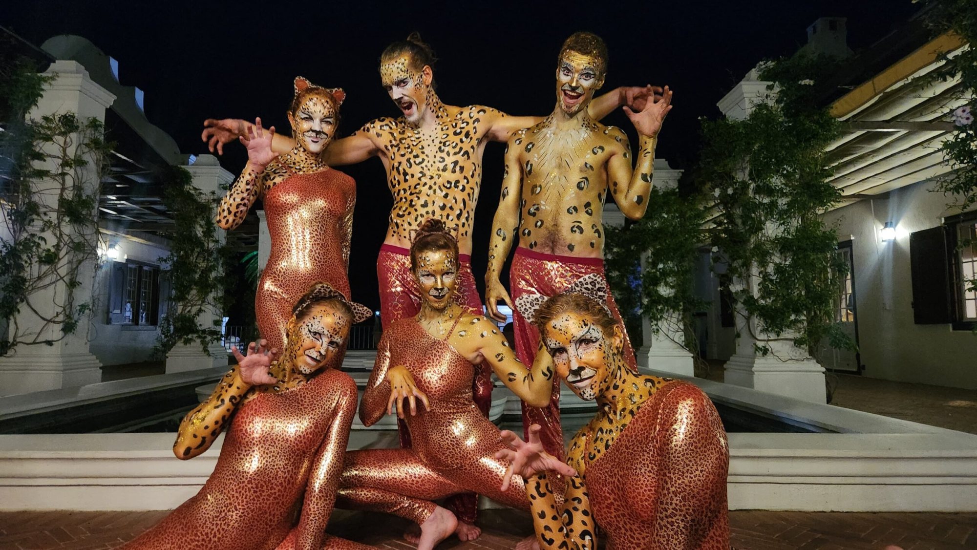 Group of performers in leopard costumes with face paint.
