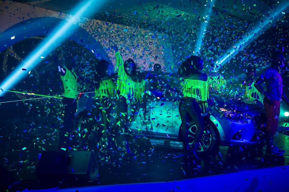 Confetti shower at an event with performers and a car