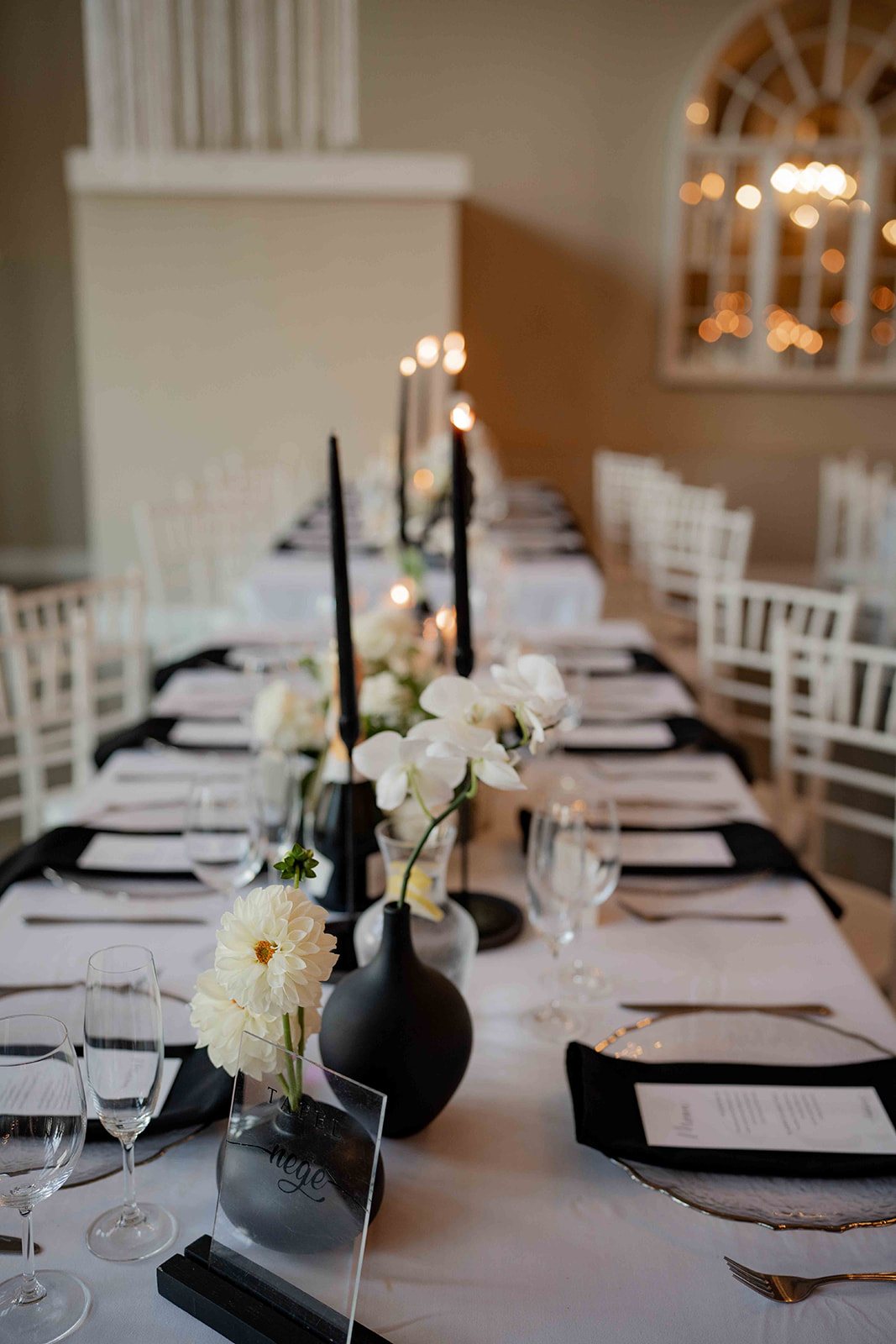 Monochromatic table setting with black candles and white flowers.