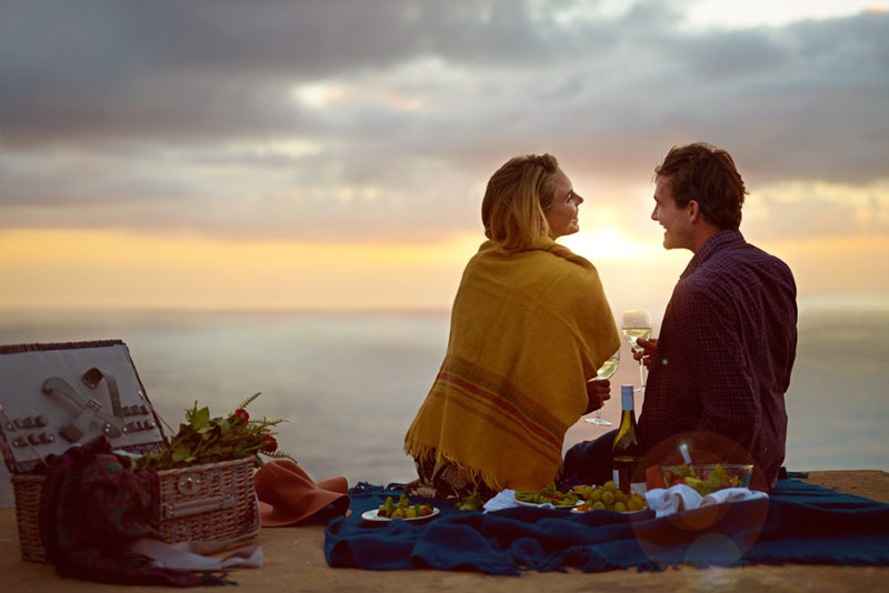 Couple having a picnic at sunset by the sea