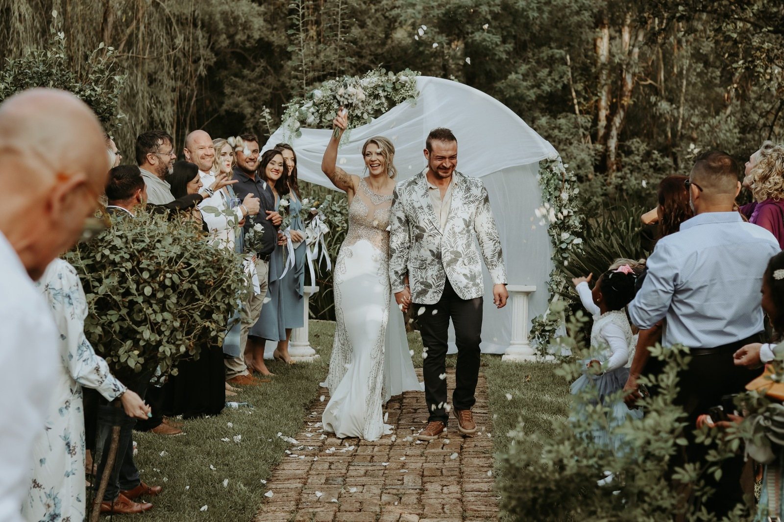 Couple celebrating their wedding in a garden, surrounded by guests.