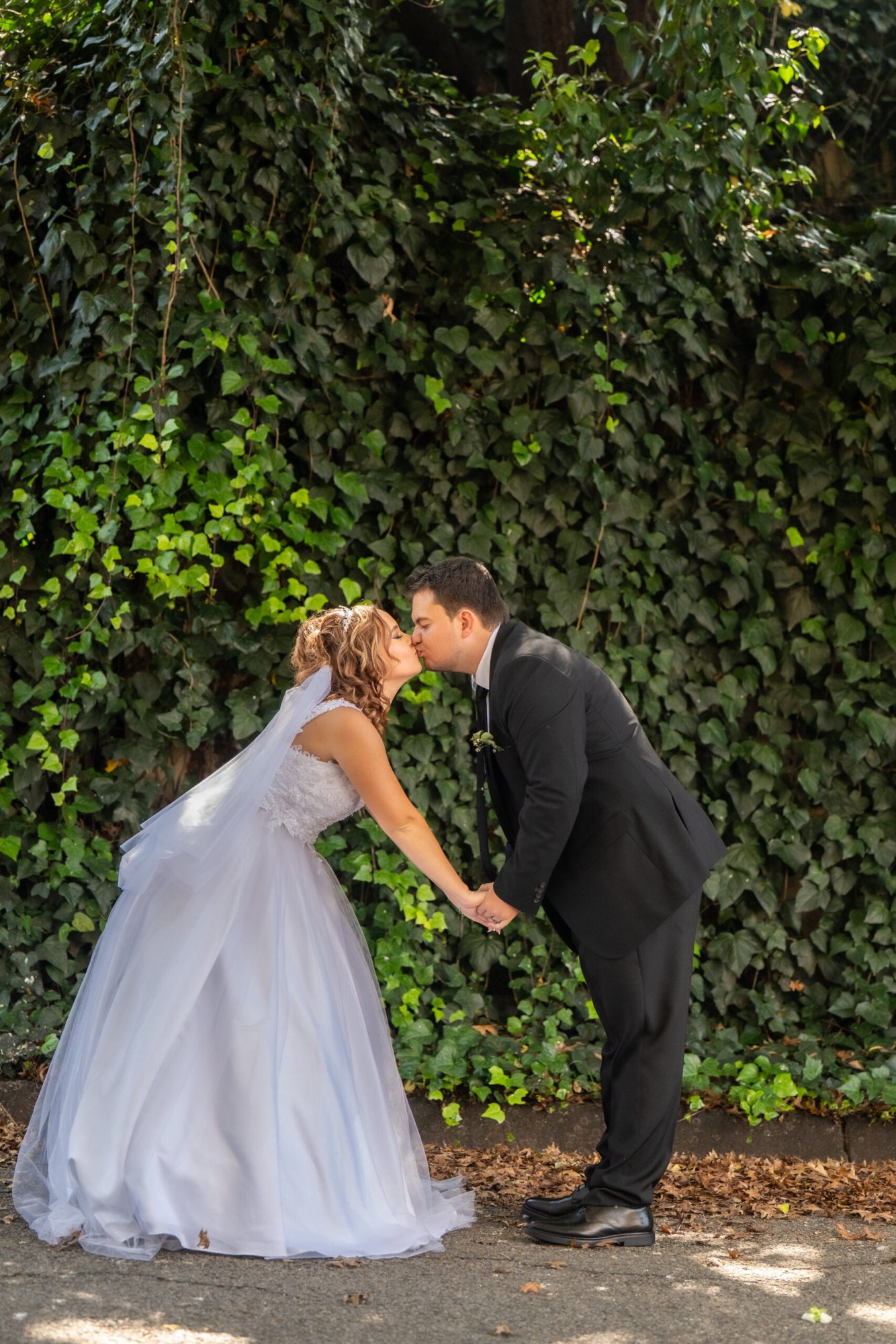 Bride and groom sharing a kiss in a green setting