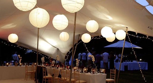 A stretch tent with lanterns and tables set for an event