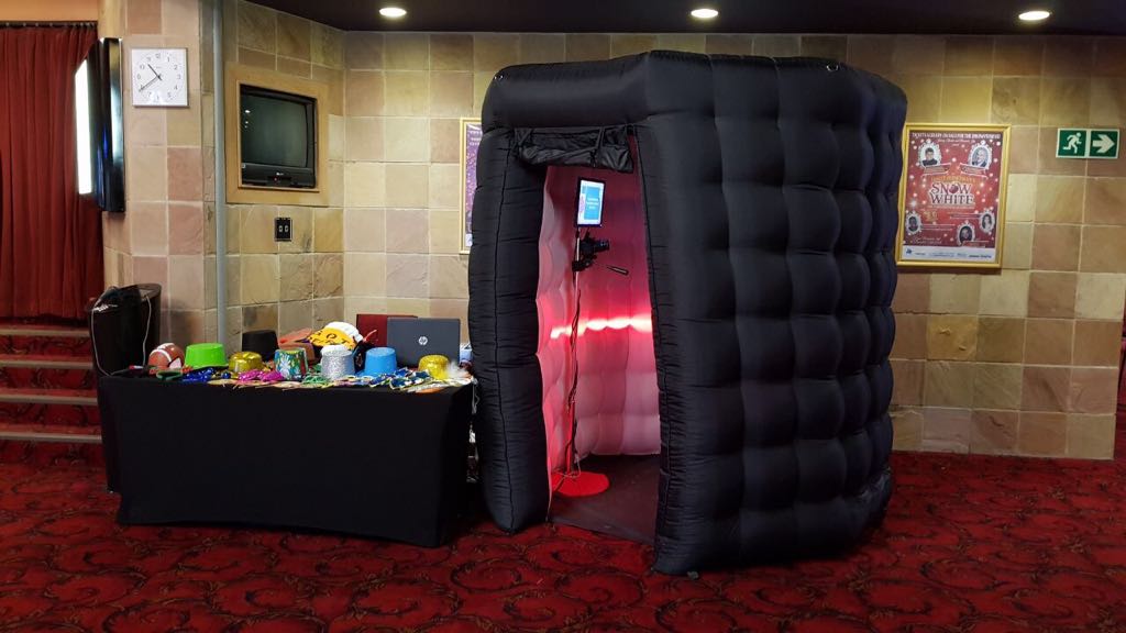 Black inflatable photo booth next to a table with colorful props
