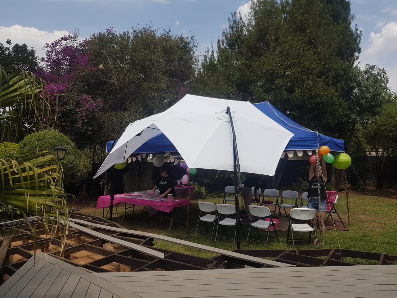 A blue and white gazebo with a decorated table and chairs for an outdoor event.