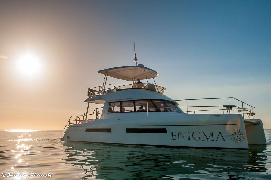 Catamaran ENIGMA sailing on calm waters during sunset