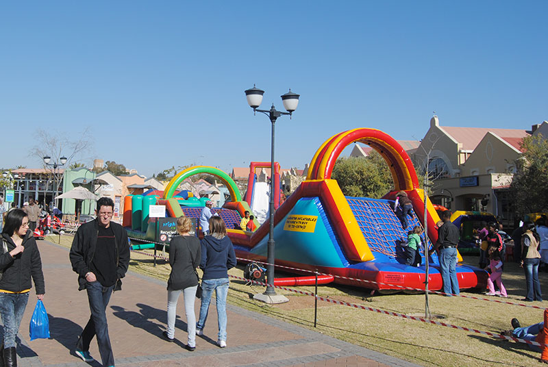 Colorful inflatable structures in a park with people nearby.