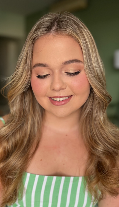Smiling woman with soft bridal makeup and loose wavy hair.