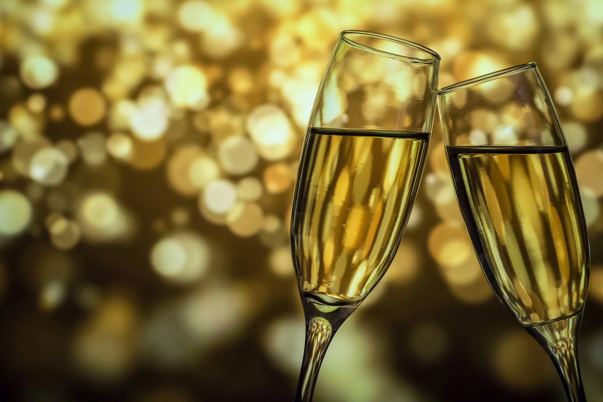 Two champagne flutes clinking with a bokeh background