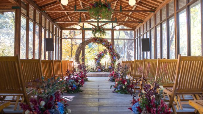 Indoor wedding ceremony setup with floral decorations and wooden seating