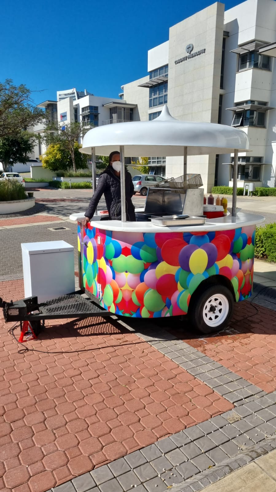 Food cart with colorful balloon design on a sunny day