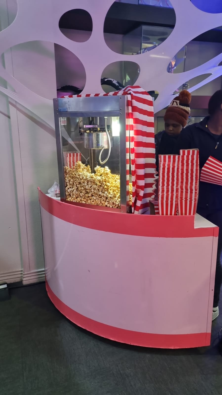 Popcorn machine with striped bags and popcorn ready to serve.