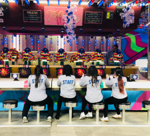 Four staff members seated at a game booth in grey shirts.